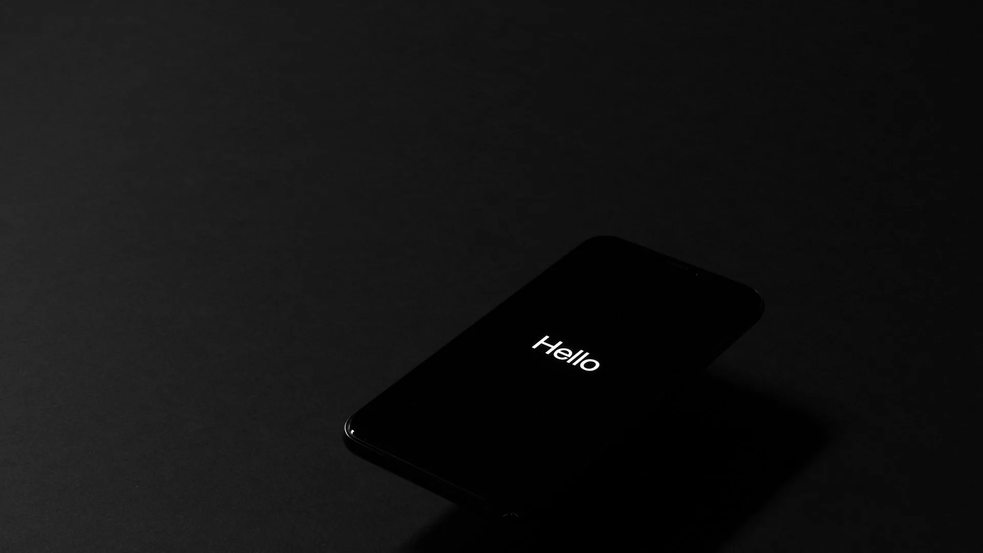 Black iPhone with a glowing screen against a dark editorial backdrop