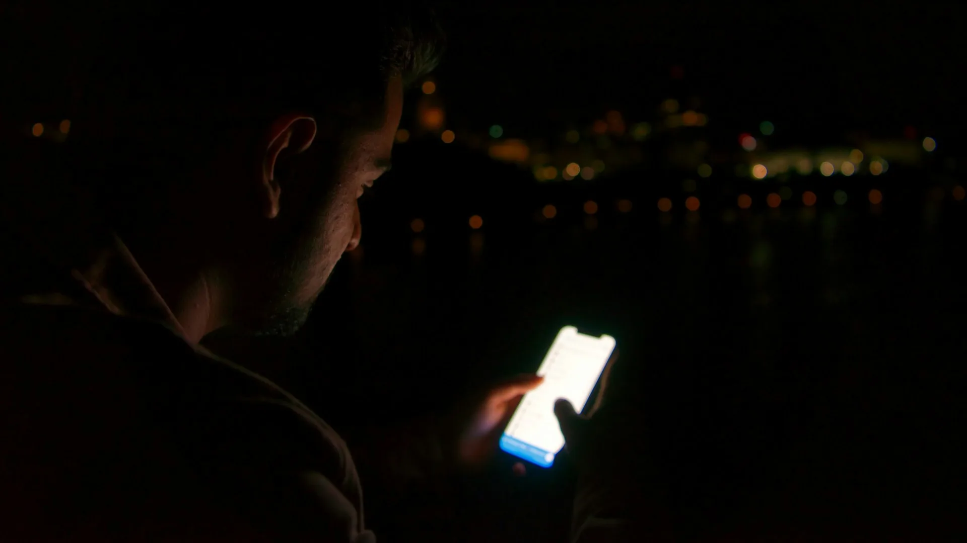 Person holding a white smartphone in a dim environment