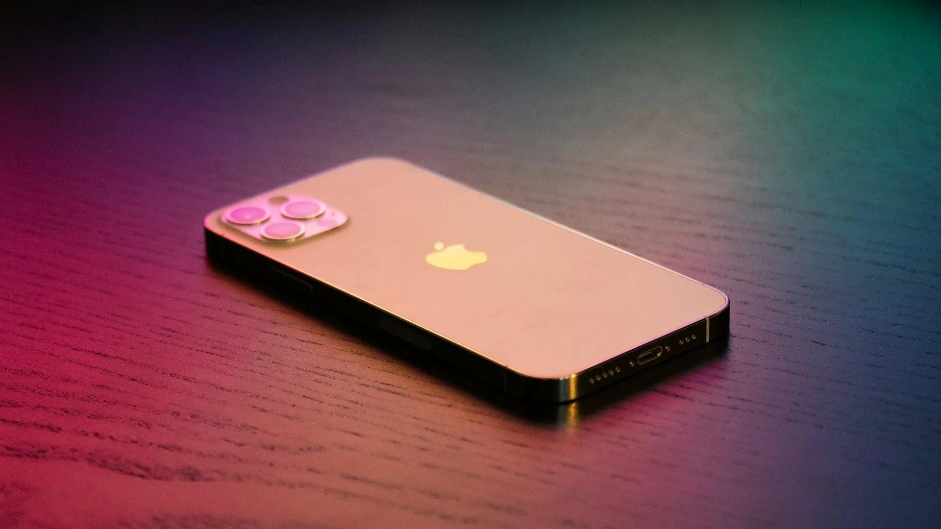 Silver iPhone resting on a wooden nightstand at night