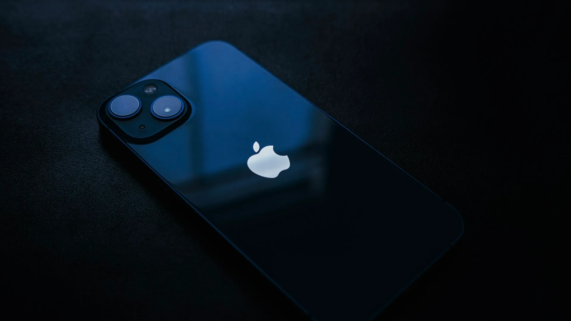Editorial close-up of an iPhone resting on a dark table