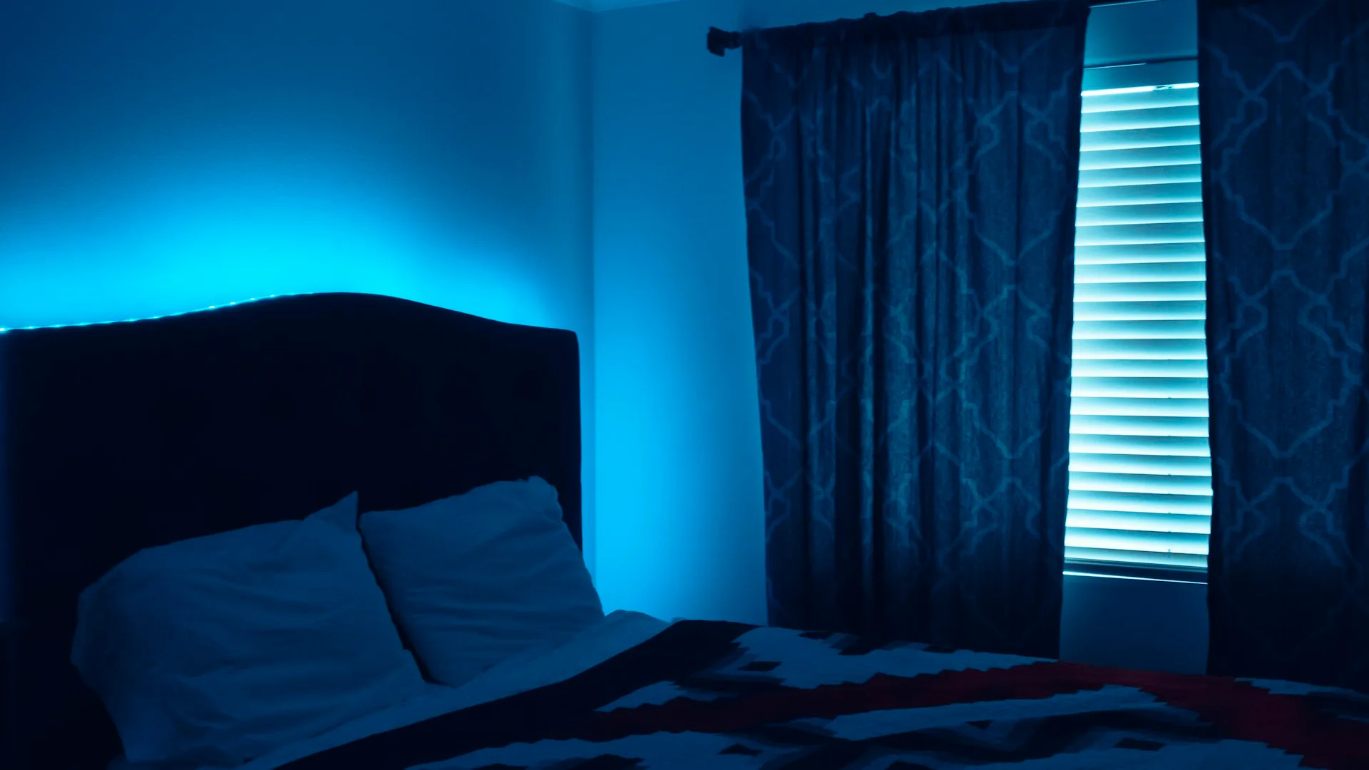 White pillow on a bed next to a window with cool light