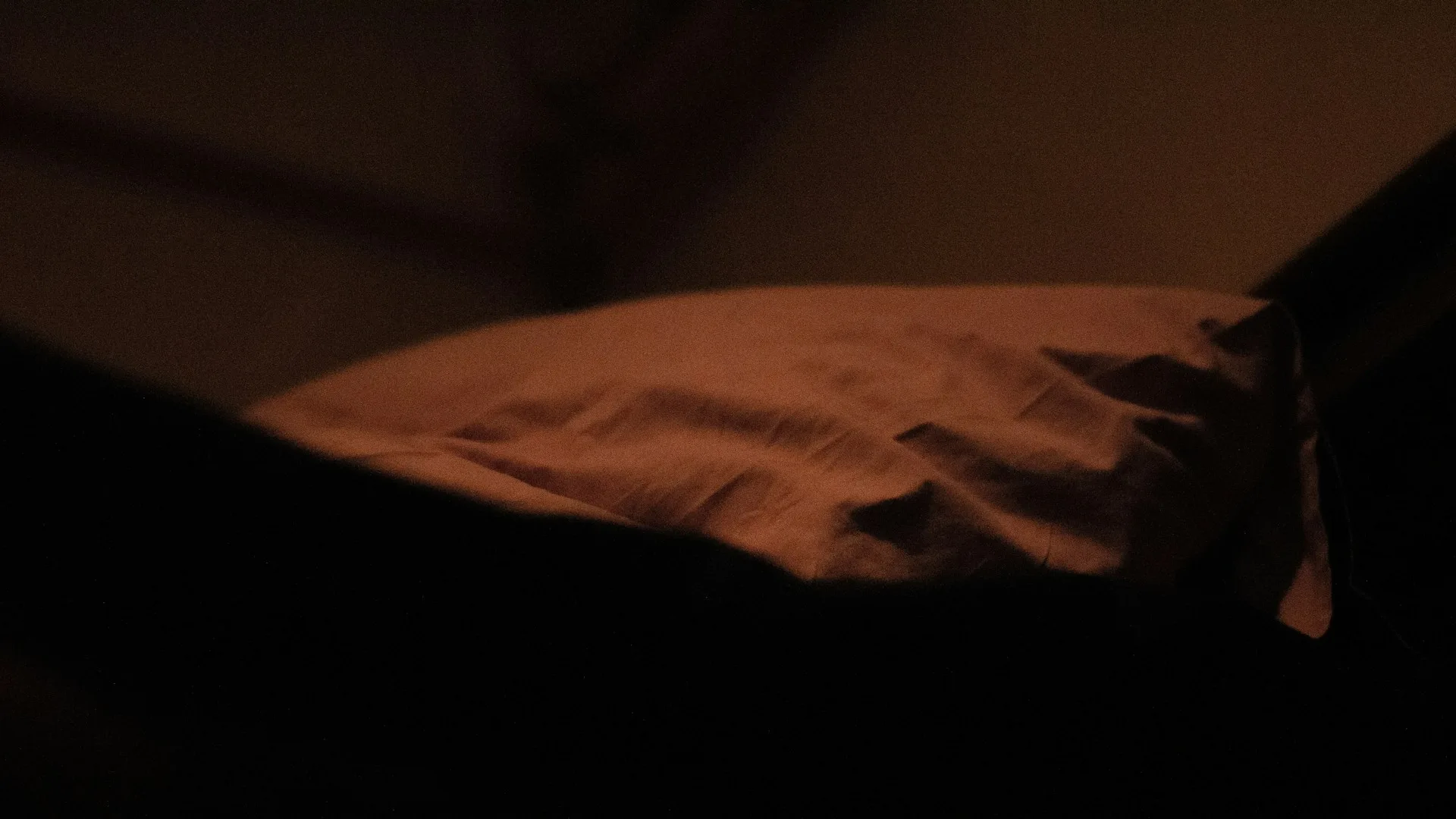 Bed made up with a plush white comforter and a black pillow