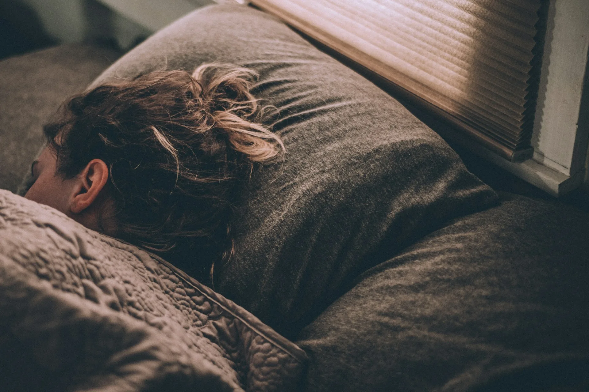 A woman sleeping peacefully in bed, lit by soft window light