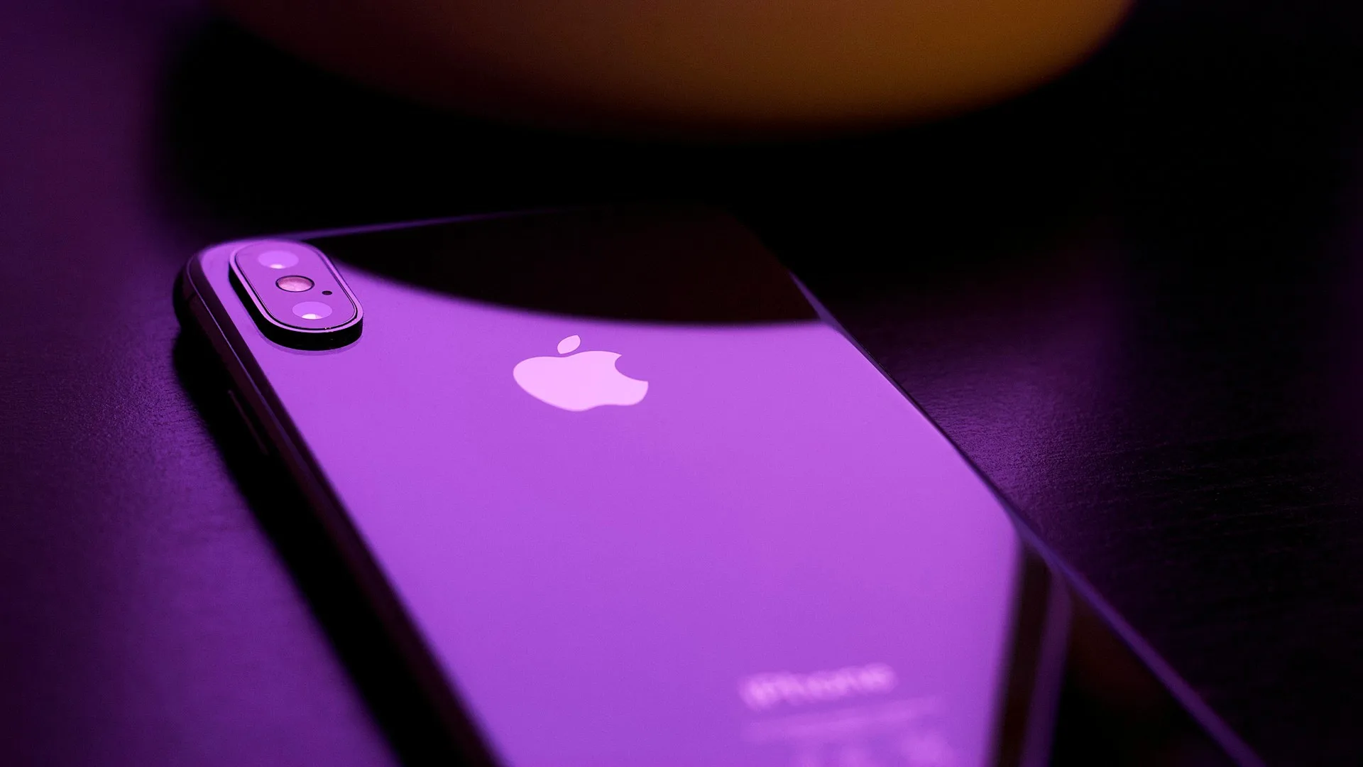 Black iPhone on a matte black surface, minimal composition